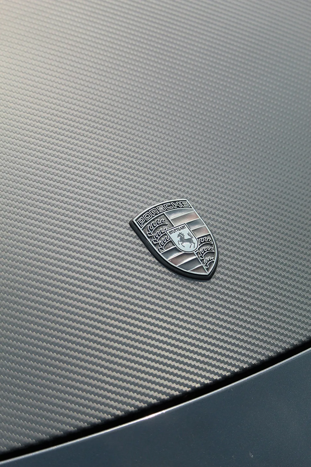 Porsche crest on exposed carbon fiber weave
