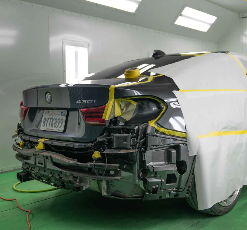 BMW 430i masked for refinishing inside the paint booth