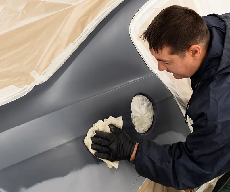 Technician hand-finishing a fiberglass bumper