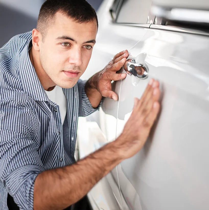 Technician pressing out a dent by hand