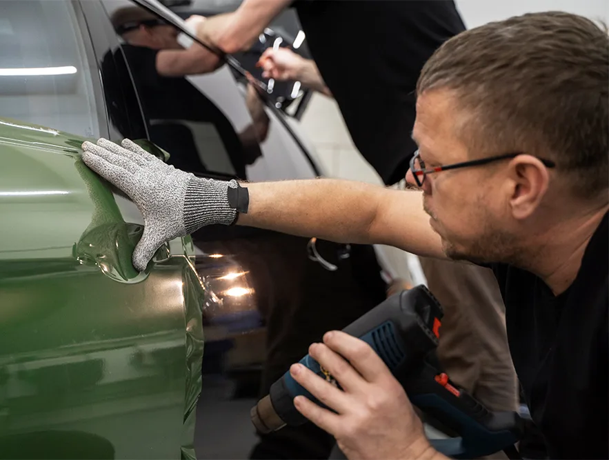 Technician working a dent on a green panel
