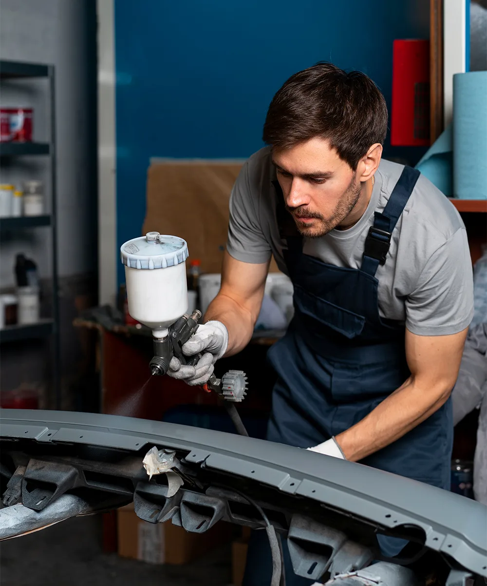 Technician spraying primer on a bumper