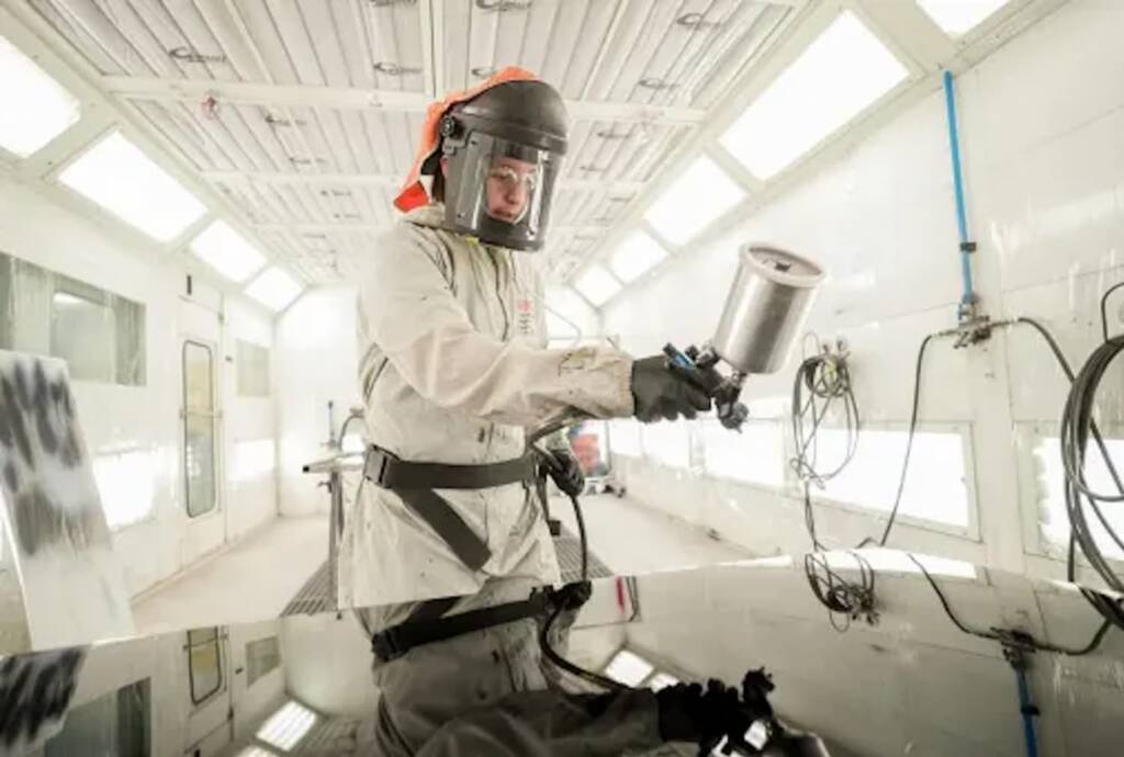 A man painting a car in a painting room