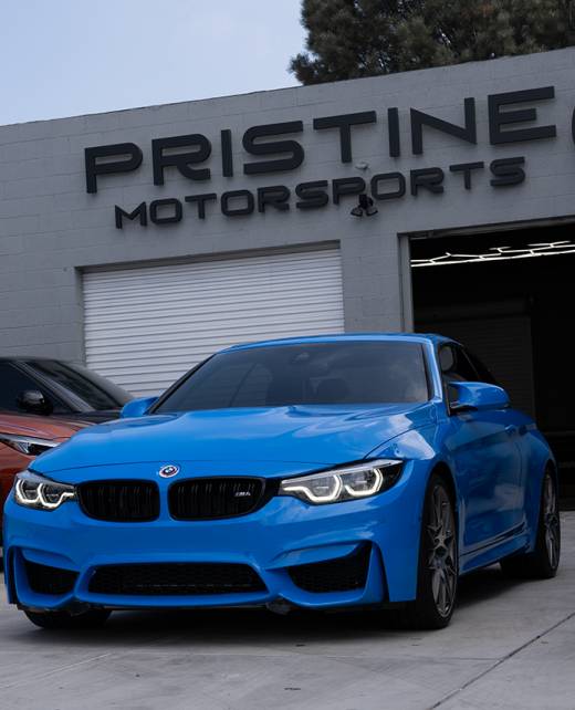 A blue BMW in front of Pristine motorsports